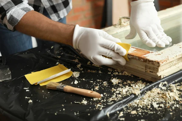 Man reparerar gamla skadade fönster vid bordet inomhus, närbild — Stockfoto