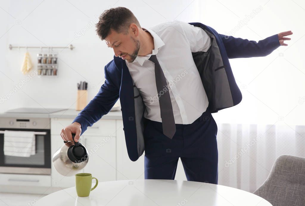 Man pouring coffee into cup in hurry at home. Morning preparatio
