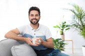 Mladý muž s šálkem nápoje relaxaci na gauči doma