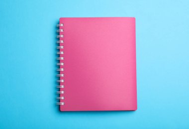 Açık mavi arkaplanda pembe defter, üst görünüm