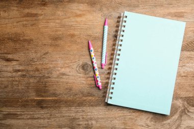 Şık bir defter ve tahta masa üzerine düz kalemler. t için boşluk