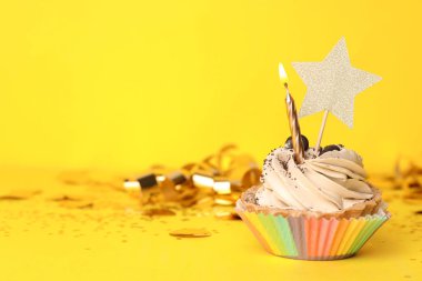 Sarı arka plan üzerinde mum ile Doğum günü cupcake, metin için alan