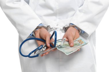 Doktor, rüşvetle kelepçelenmiş ve steteskop takmış.