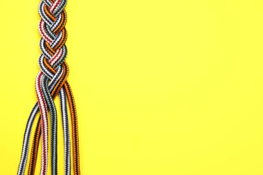 Sarı arkaplanda örülmüş renkli iplerin üst görünümü, metin için boşluk. Birlik kavramı