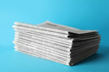 Açık mavi arka planda bir yığın gazete. Gazeteci işi.