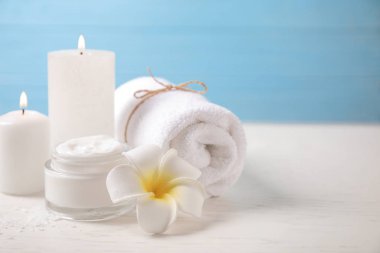 Kremalı kompozisyon ve beyaz ahşap masada yanan mumlar. Spa tedavisi