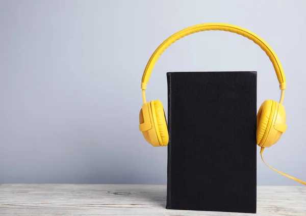 Boek en moderne koptelefoon op witte houten tafel. Ruimte voor tekst — Stockfoto