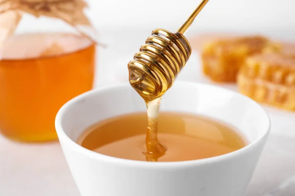 テーブルの上のボウルにディップからおいしい蜂蜜を滴下 クローズアップ — ストック写真