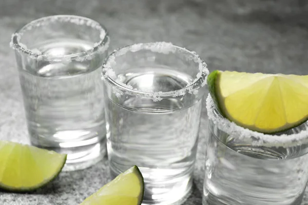 Mexikói Tequila Feles Sóval Lime Szeletekkel Szürke Asztalon Közelkép — Stock Fotó