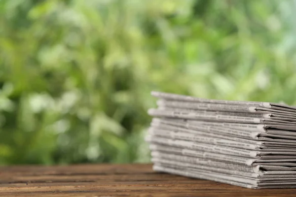 Tahta Masadaki Gazete Yığını Bulanık Yeşil Arka Plana Karşı Yazı — Stok fotoğraf