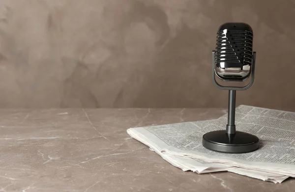 Newspapers and vintage microphone on marble table, space for tex