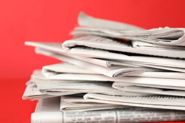 Kırmızı arka planda gazete yığını, yakın plan. Gazeteci sözü.