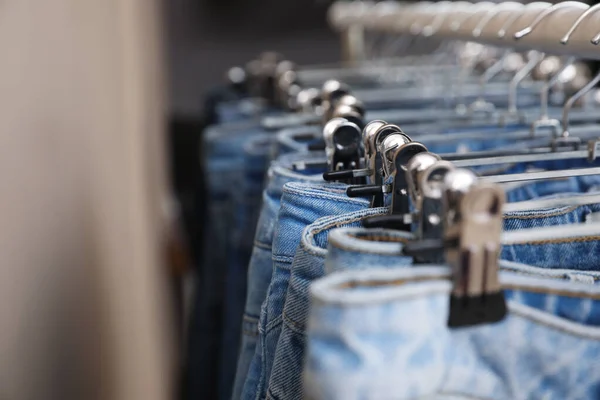 Hangers with stylish jeans near beige wall, closeup — 스톡 사진