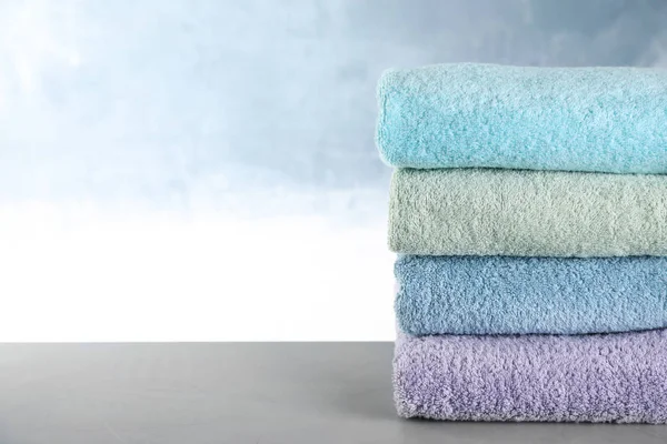 Pila di asciugamani puliti sul tavolo grigio. Spazio per testo — Foto Stock