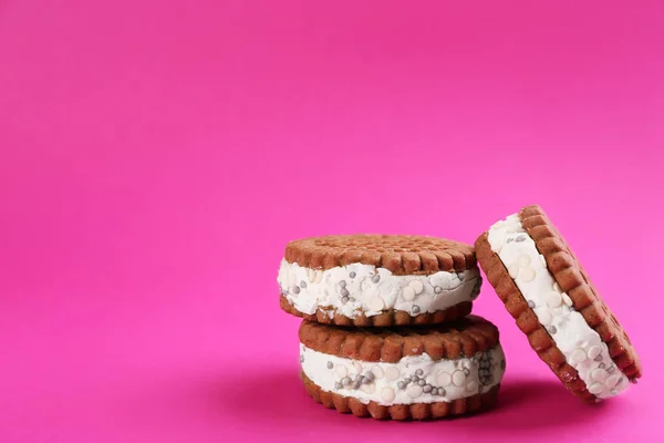 Sweet delicious ice cream cookie sandwiches on pink background. Space for text