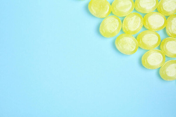 Many delicious lemon drops on light blue background, flat lay. S