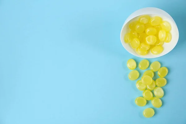 Delicious lemon drops and bowl on light blue background, flat la — 스톡 사진