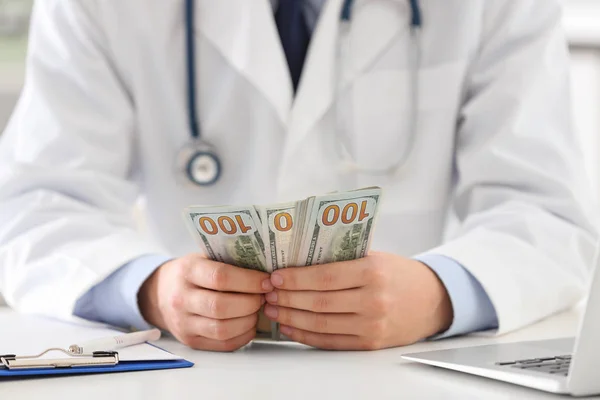 Doctor with bribe at desk in clinic, closeup. Corrupted medicine — Stock Photo, Image