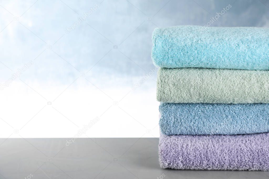 Stack of clean bath towels on grey table. Space for text