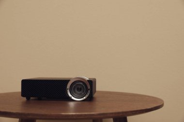 Modern video projektörü ahşap masada, bej arka planda. Metin için boşluk