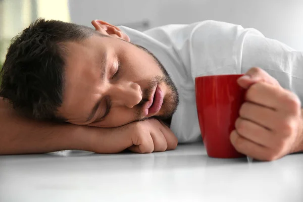 Homem com xícara de bebida dormindo em casa de manhã — Fotografia de Stock