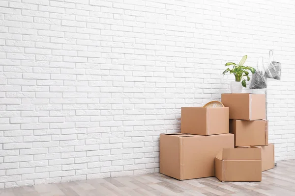 Pilha Caixas Papelão Planta Sala Perto Parede Tijolo Branco Espaço — Fotografia de Stock