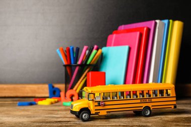 Okul otobüsü modeli ve ahşap masadaki kırtasiye malzemeleri. s için aktarım