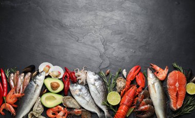 Fresh fish and different seafood on black table, flat lay. Space for text clipart