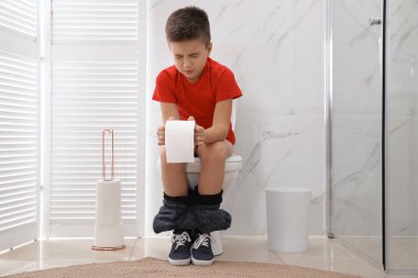 Tuvaletteki hemoroitten muzdarip kâğıtlı çocuk.