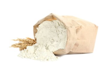 Overturned paper bag of flour and spikelets isolated on white