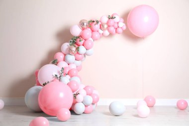 Bej duvarın yanında balonlar ve yeşil yapraklarla güzel bir kompozisyon.