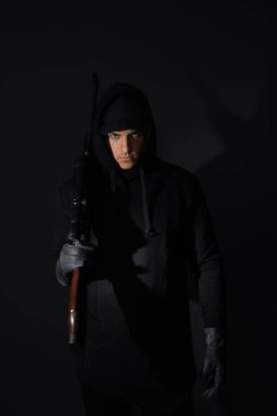 Siyah arka planda keskin nişancı tüfeği olan profesyonel bir katil.