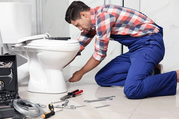 Fontanero profesional trabajando con inodoro en el baño — Foto de Stock