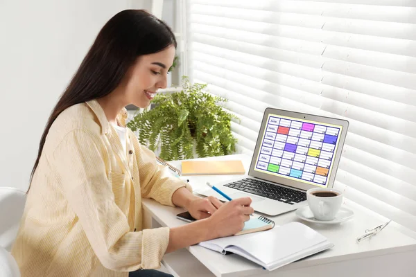 Ung kvinna planerar sitt schema med kalender app på laptop i — Stockfoto