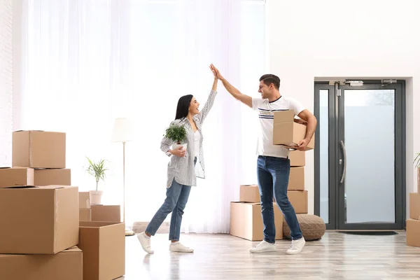 Happy couple in room with cardboard boxes on moving day — Stock Photo, Image