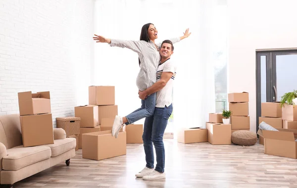 Happy couple having fun in room with cardboard boxes on moving d — 스톡 사진