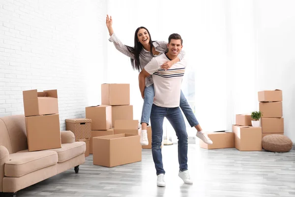 Happy couple having fun in room with cardboard boxes on moving d — Stock Photo, Image