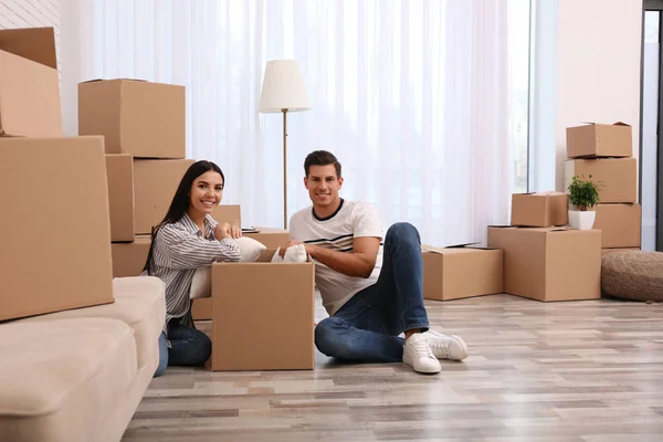 Feliz pareja desempacando cajas de cartón en su nuevo piso en movi —  Fotos de Stock