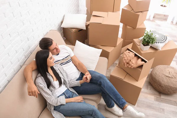 Happy couple resting in room with cardboard boxes on moving day, — 스톡 사진