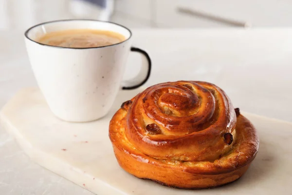 Delicious bun and coffee on light table. Sweet pastries