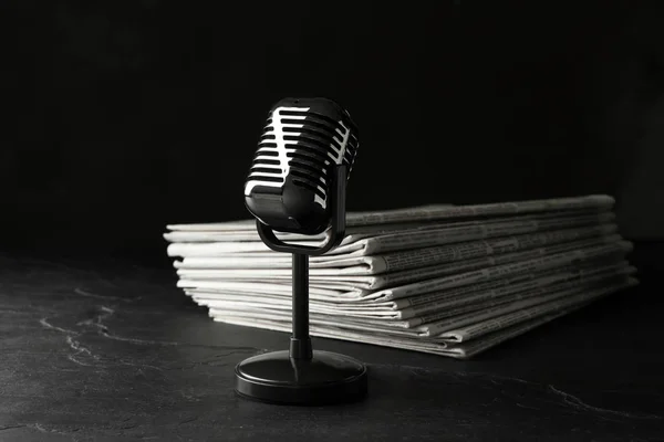 Εφημερίδες και vintage μικρόφωνο σε σκούρο πέτρινο τραπέζι. Δημοσιογραφία — Φωτογραφία Αρχείου