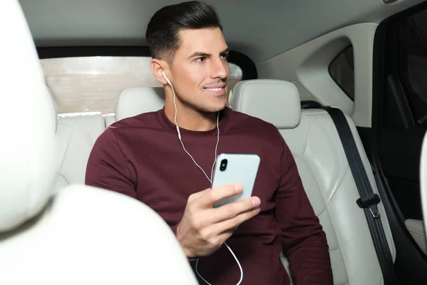 Hombre con teléfono móvil escuchando audiolibro en el coche — Foto de Stock