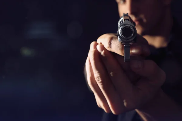 Professional killer with gun on black background, closeup. Space — Stock Photo, Image