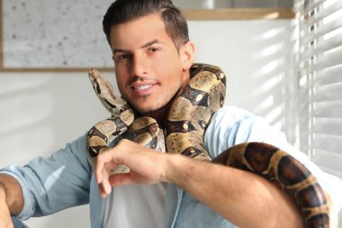 Evde boa yılanı olan bir adam. Egzotik hayvan