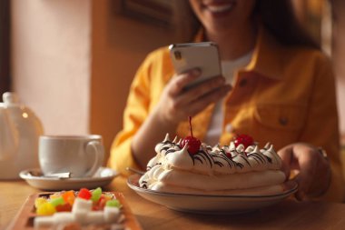 Genç blogcu, kafede tatlıların fotoğrafını çekiyor, tabağa odaklanıyor.