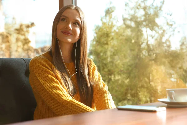 Mujer escuchando audiolibro en la mesa en la cafetería — Foto de Stock