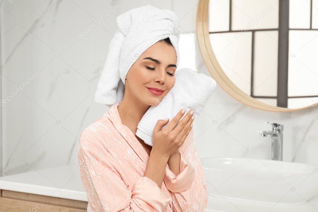Young woman wiping face with towel in bathroom