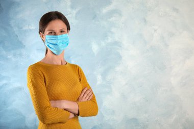 Yüzü açık mavi arka planda tek kullanımlık maskeli bir kadın. Metin için boşluk