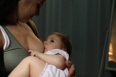 Kadın bebeğini evde emziriyor.