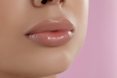 Pembe arka planda güzel dolgun dudakları olan genç bir kadın, yakın plan.